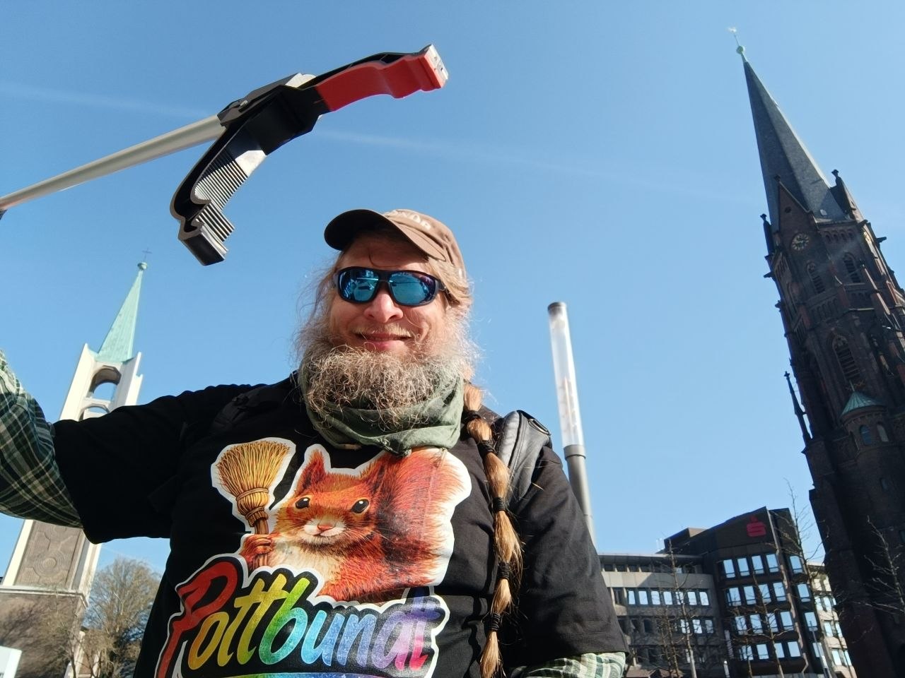 Eine Person mit Greifzange und Pottbundt-Shirt bei einer Aktion im Stadtraum